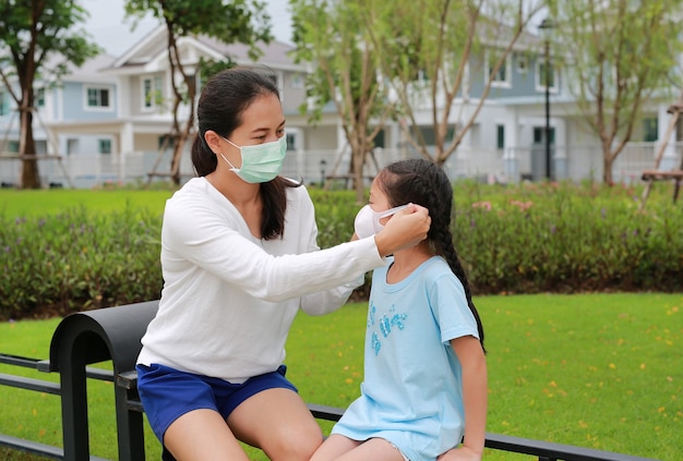 Madre asiática con máscaras de protección para su hija en el jardín público durante el brote de coronavirus y gripe