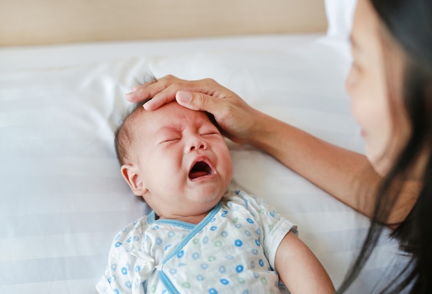 Madre asiática que consuela a su hijo enojado en la cama.