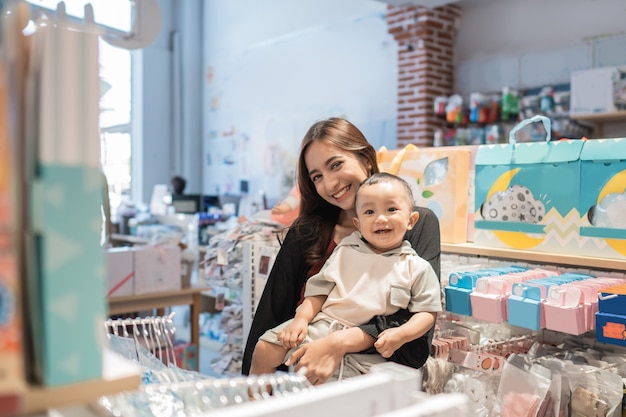 Madre asiática con su niño pequeño de compras en la tienda del bebé