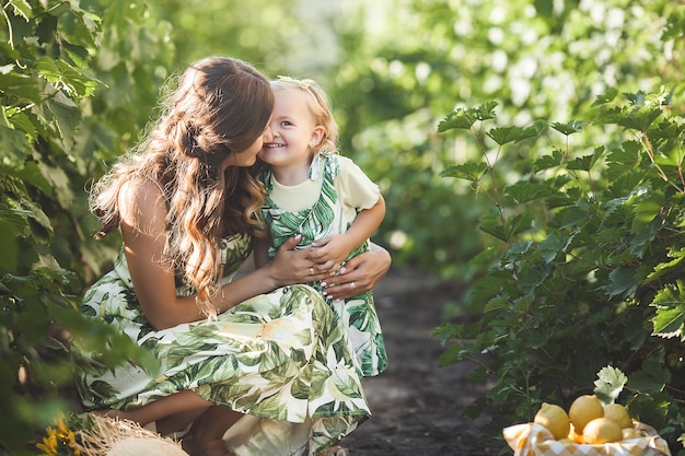 Madre atractiva joven y su pequeña niña al aire libre.