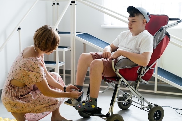 Madre ayuda a niño discapacitado con parálisis cerebral en silla de ruedas