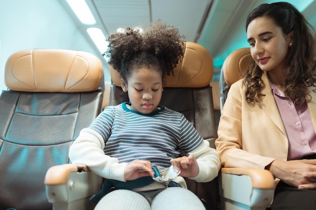 Una madre ayuda a su hijo a atarse el cinturón de seguridad para mantenerlo a salvo durante un vuelo