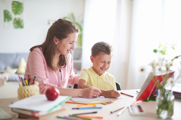 Madre ayuda a su hijo a hacer lecciones. escuela en casa