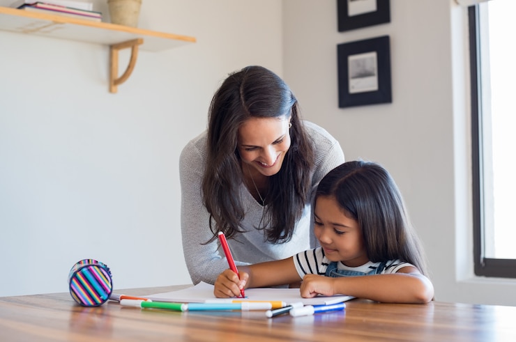 Foto madre ayudando a dibujar hija