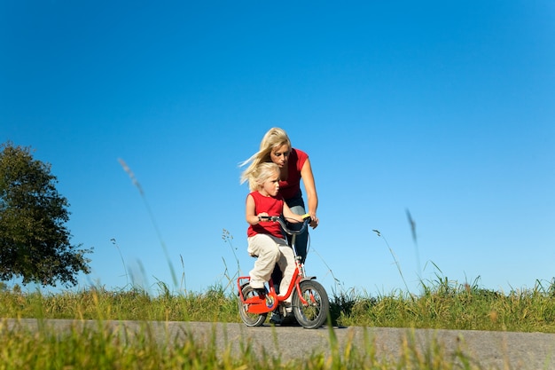 madre ayudando a su hija a andar en bicicleta