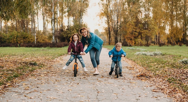 Foto madre ayudando a sus hijos a andar en bicicleta