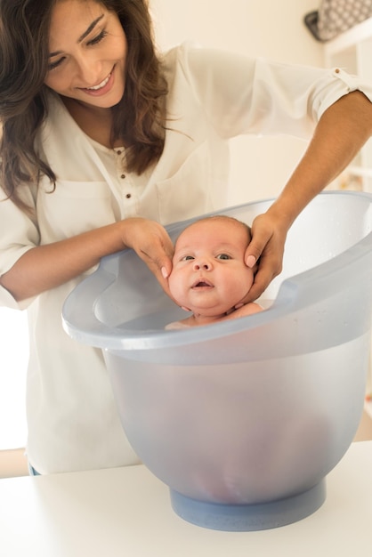 Madre bañando a su hijo en la bañera en el baño