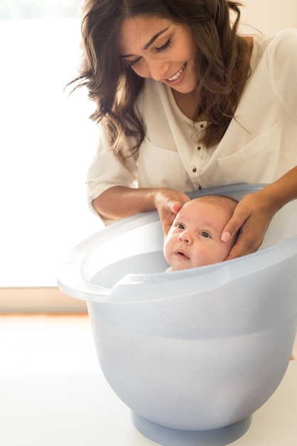Madre bañando a su hijo en la bañera en el baño