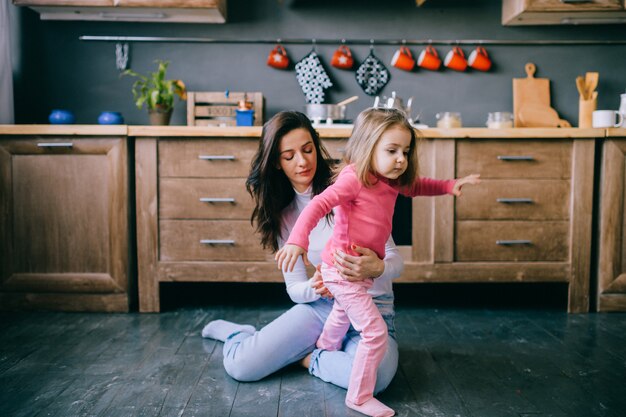 Madre bastante joven con su pequeña hija en la cocina