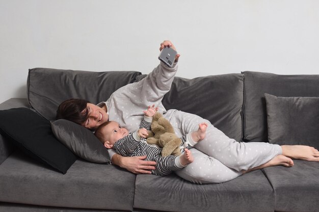 Madre y bebé acostado en el sofá haciendo un selfie