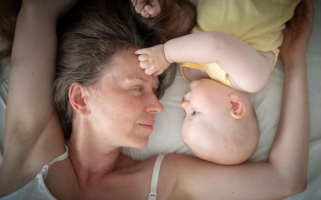 Foto madre y bebé se acuestan en la cama vista superior concepto de maternidad día de la madre