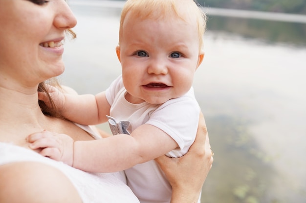 Madre con bebé al aire libre cerca del río. El concepto de familia feliz