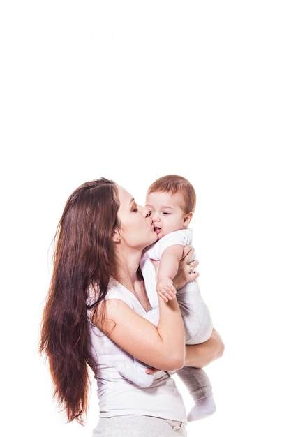 Madre y bebé besándose y abrazándose, aislado en blanco. Familia feliz