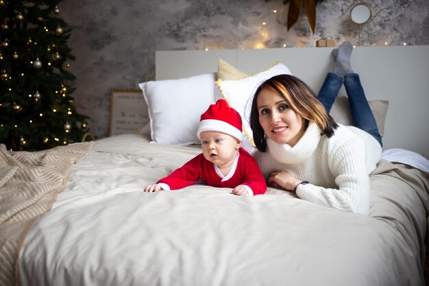 Madre y bebé en cama en casa en vacaciones de Navidad