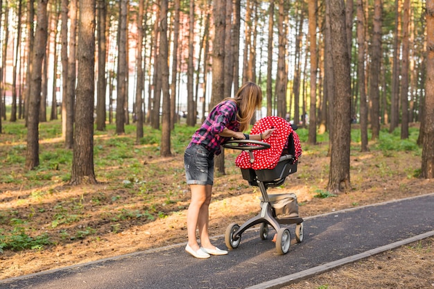 Madre con bebé en cochecito caminando en el parque de verano