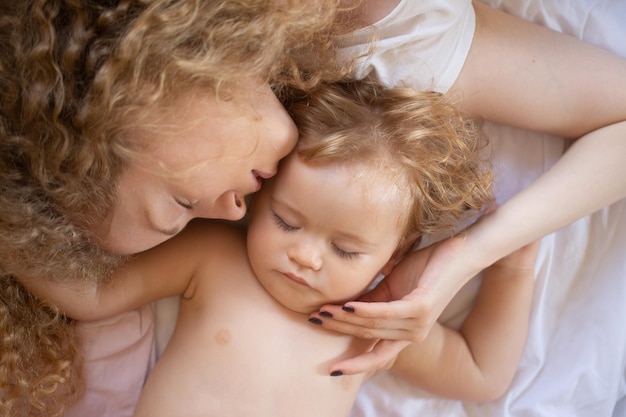 Madre y bebé durmiendo en la cama por la mañana