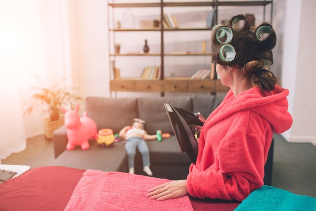 Madre y bebé juntos dedicados a las tareas del hogar Planchado de ropa. Ama de casa y niño haciendo los deberes