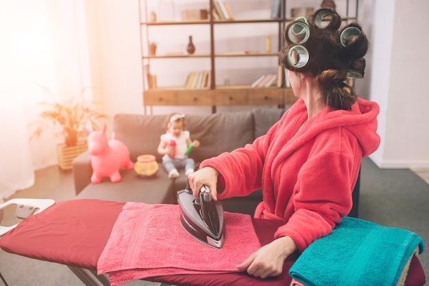 Foto madre y bebé juntos dedicados a las tareas del hogar planchado de ropa. ama de casa y niño haciendo los deberes