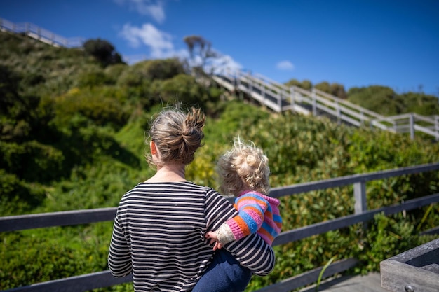 La madre y el bebé en el paseo marítimo de madera de vacaciones