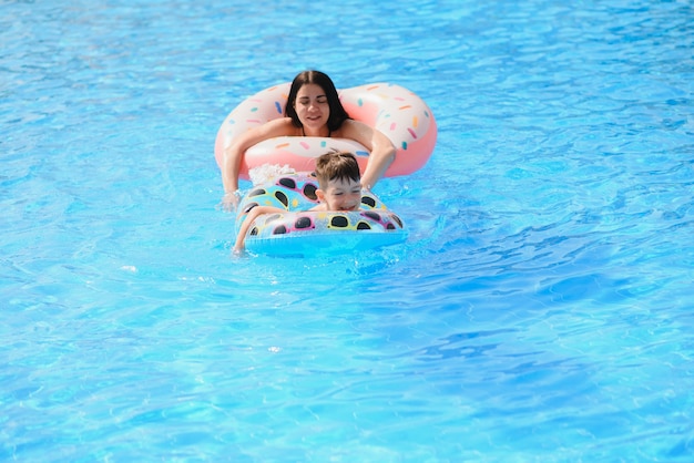 Madre y bebé en la piscina al aire libre del resort tropical.