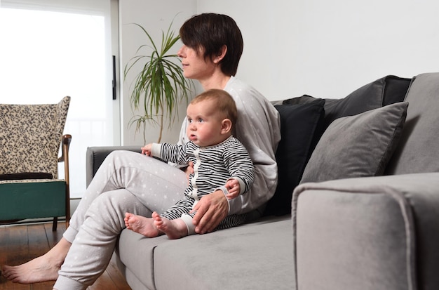 Madre y bebé sentados en el sofá mirando