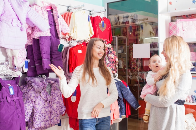 Madre con bebé visita la tienda de ropa con ropa de invierno.