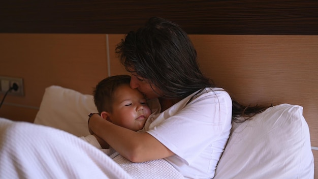 La madre besa a su hijo pequeño en la cama para darle las buenas noches o los buenos días Estilo de vida familiar feliz