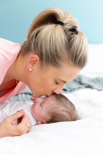 Foto madre besando a su niña en la cama en casa