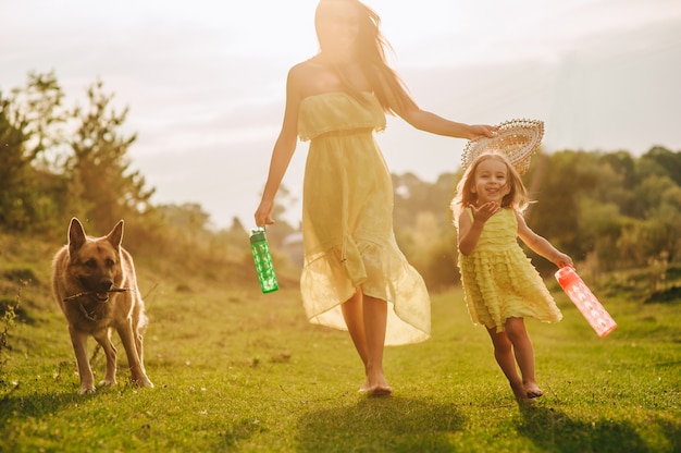 La madre camina con su hijita, y su perro.