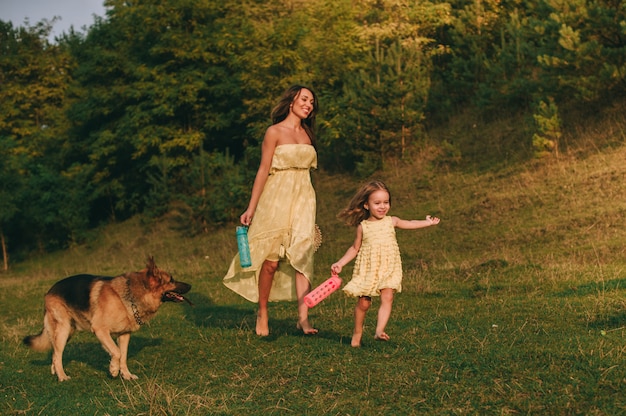 La madre camina con su hijita, y su perro.