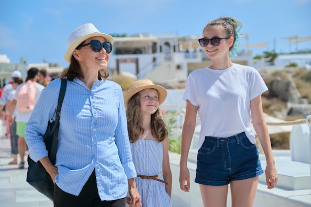 Madre caminando con dos hijas de la mano en la famosa localidad turística de Oia en la isla de Santorini