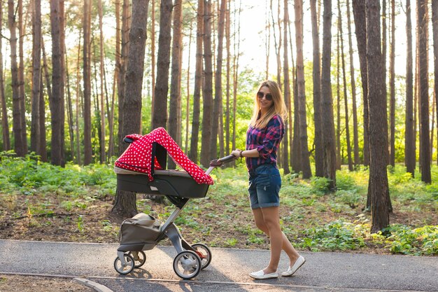 Madre caminando mientras empuja un cochecito en el parque.