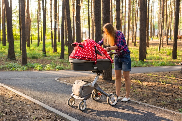 Madre caminando mientras empuja un cochecito en el parque.