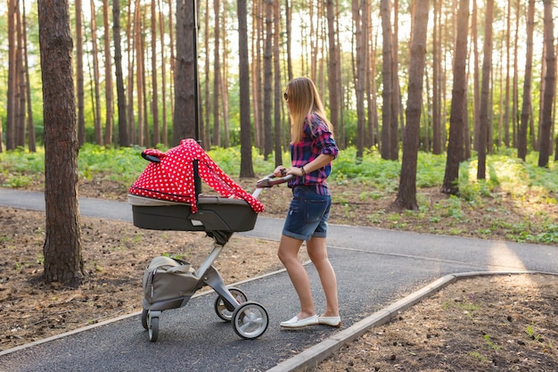 Madre caminando mientras empuja un cochecito en el parque.