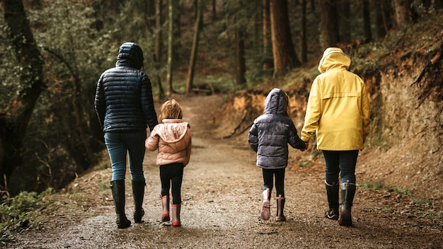 Madre caminando con sus hijas en la vista trasera del bosque