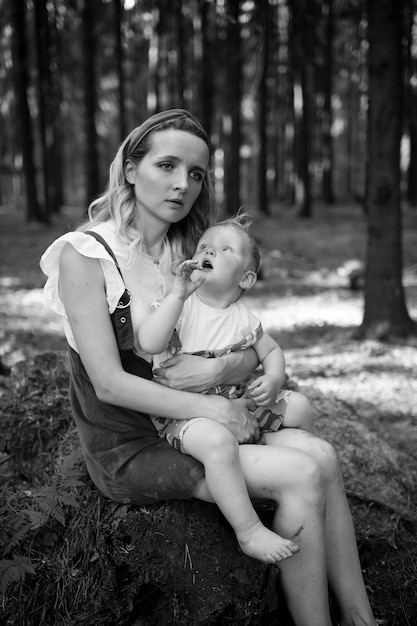 Madre cansada posando con su gracioso hijo en el bosque