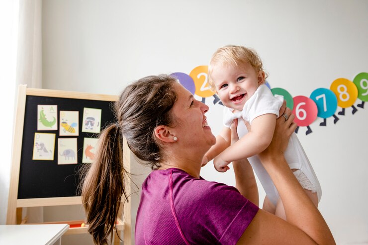 Foto madre cargando y jugando con su bebé.
