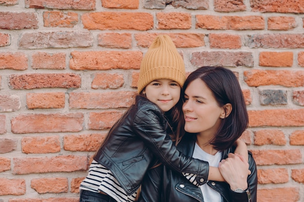 Madre cariñosa con cabello oscuro recibe cálido abrazo de hija