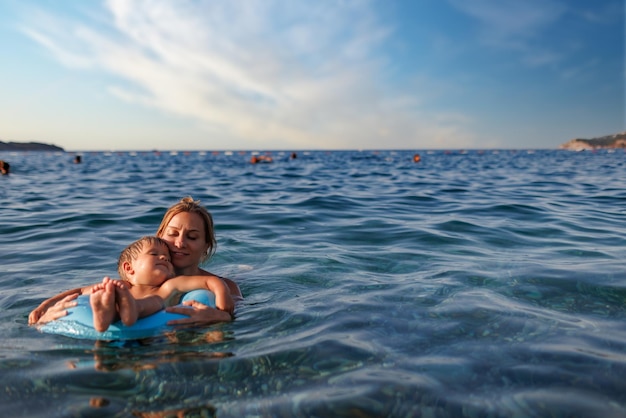 Madre cariñosa monta a su hijo en un anillo inflable en el mar