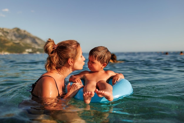 Madre cariñosa monta a su hijo en un anillo inflable en el mar