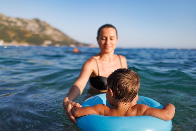 Madre cariñosa monta a su hijo en un anillo inflable en el mar