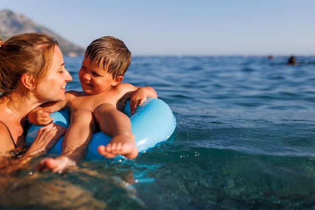 Madre cariñosa monta a su hijo en un anillo inflable en el mar