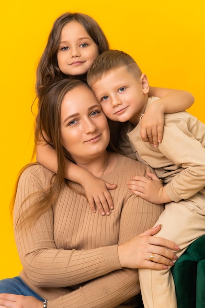 Madre cariñosa con sus hijos en un fondo amarillo