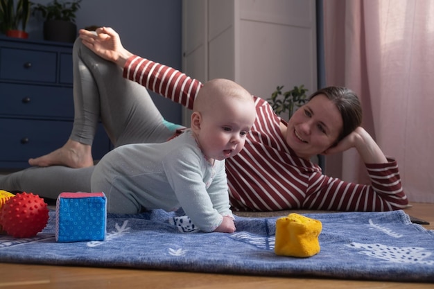 Madre caucásica con bebé hace yoga en casa para ser fuerte y saludable