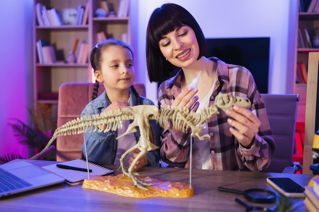 Madre caucásica ensambla el esqueleto de un dinosaurio con una hija linda y inteligente