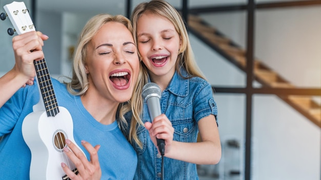 Madre caucásica con niña cantando en karaoke en casa