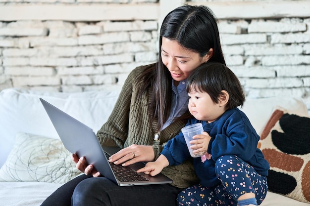 Madre china y niño sonriendo en la pantalla de la computadora portátil tiempo alegre