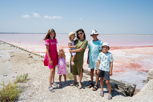 Madre con cinco hijos contra el lago salado rojo en Saline Margherita di Savoia de Italia