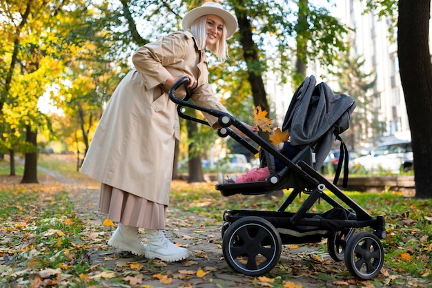 Madre con cochecito de bebé caminando en el parque