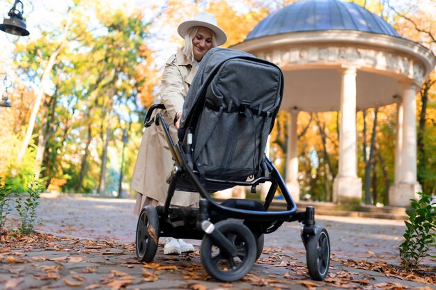 Madre con cochecito de bebé caminando en el parque